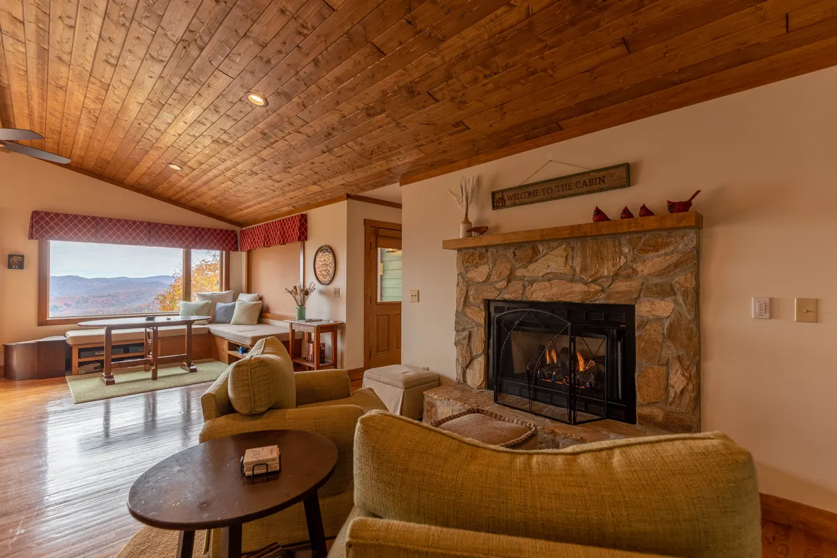 A comfortable living area with a fireplace, ample seating, and a large window showcasing beautiful mountain vistas. The open floor plan and uncluttered pathways highlight ease of movement for guests with mobility needs.