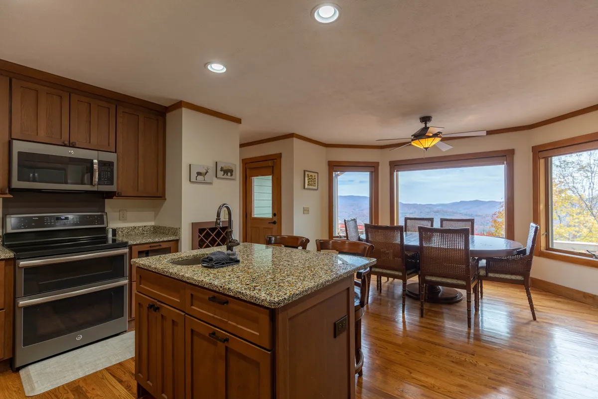 The kitchen and dining area are open and filled with light from panoramic windows. A kitchen island and a dining table create a seamless flow for cooking, eating, and spending time together, all while enjoying beautiful views.