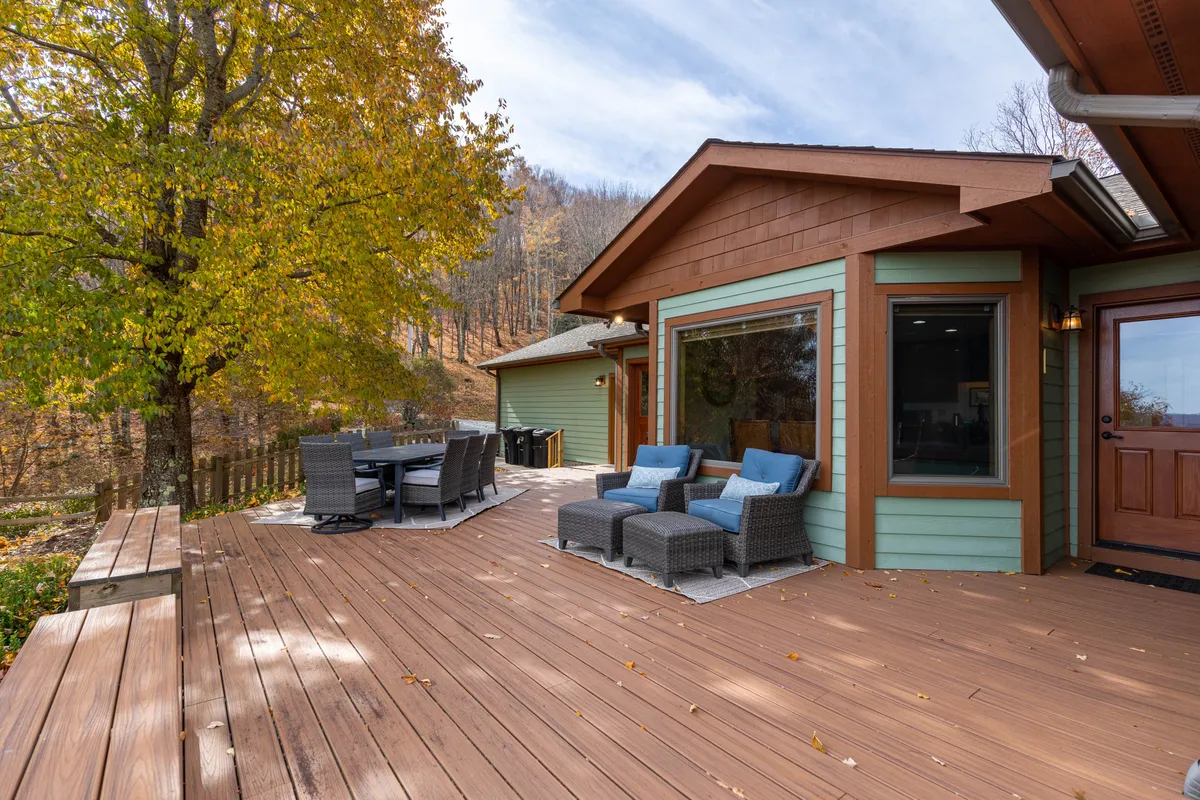 A comfortable deck seating area with a dining table nestled among surrounding trees. The setup encourages outdoor dining, relaxation, and social gatherings, with the natural setting enhancing the sense of retreat.