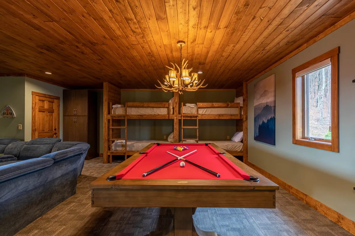 Featuring a close-up of the pool table and adjacent bunk beds under the glow of a chandelier, this image spotlights the playful spirit of the entertainment suite. The arrangement invites friendly competition and hints at the vibrant family activity that takes place here.