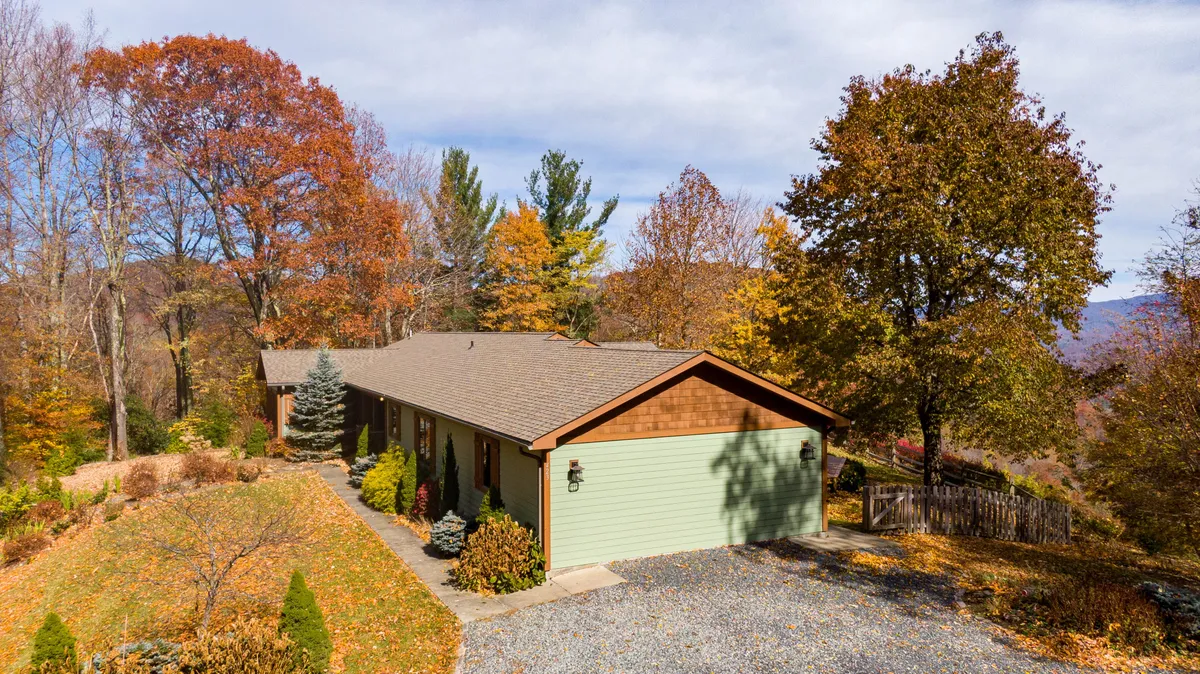 A serene view of the house surrounded by autumn foliage, with a stone pathway leading toward the entrance. The scene suggests a tranquil retreat nestled in nature, and hints at the proximity to local attractions and activities.