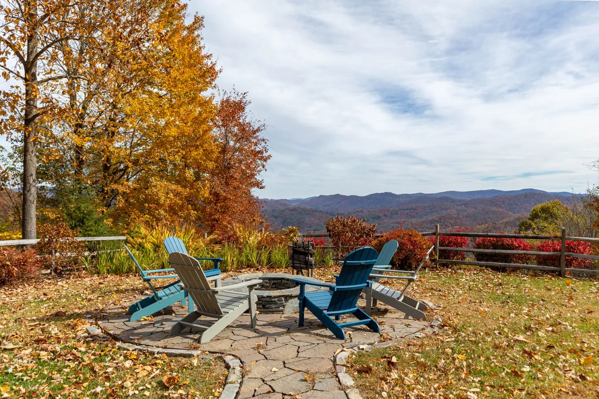 This image features a fire pit surrounded by Adirondack chairs with a stunning mountain view and vibrant autumn foliage. The setting highlights an inviting space for gathering, storytelling, and enjoying nature, perfectly framed by the golden hour light.